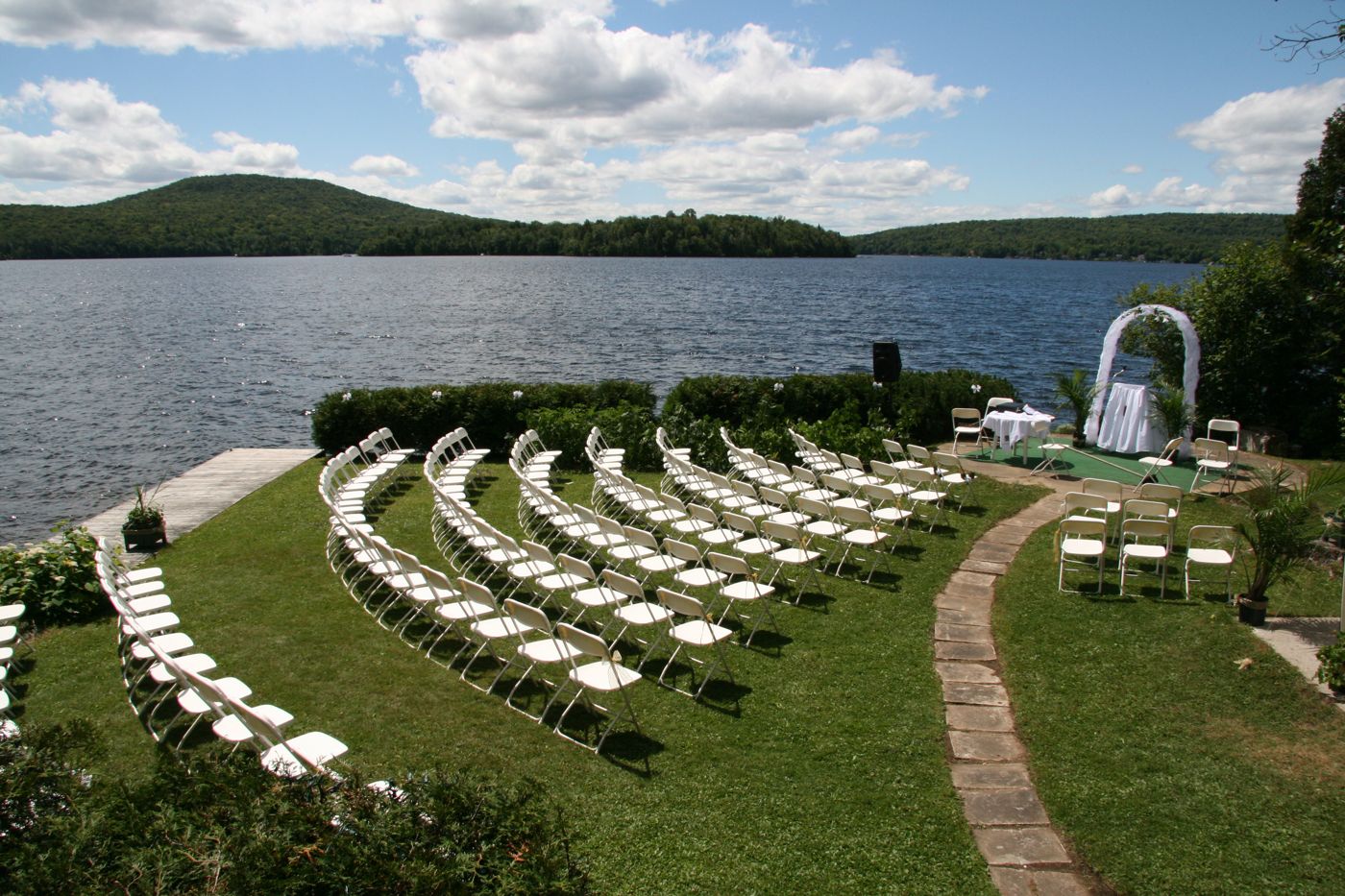 Rows of white chairs on a lawn facing a lake, set up for an outdoor ceremony